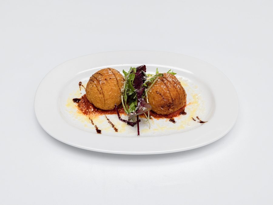 Golden fried arancini on a bed of tomato sauce