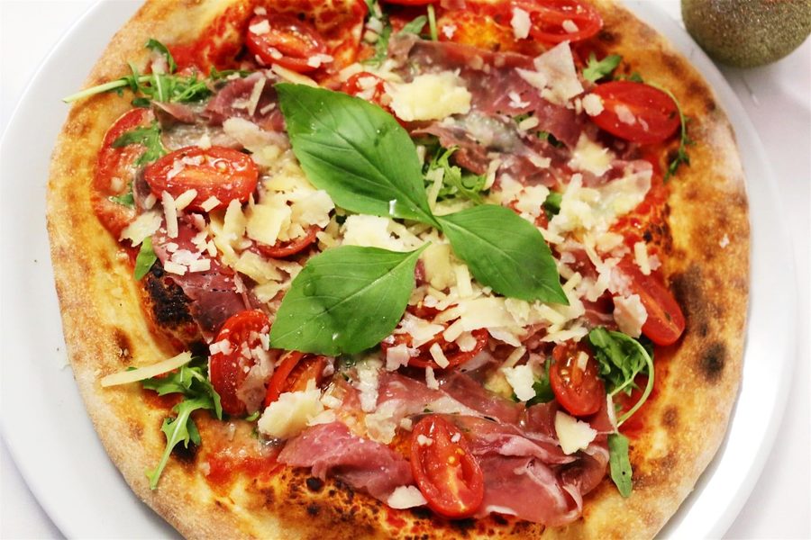 A stone-baked pizza with tomato, mozzarella and basil
