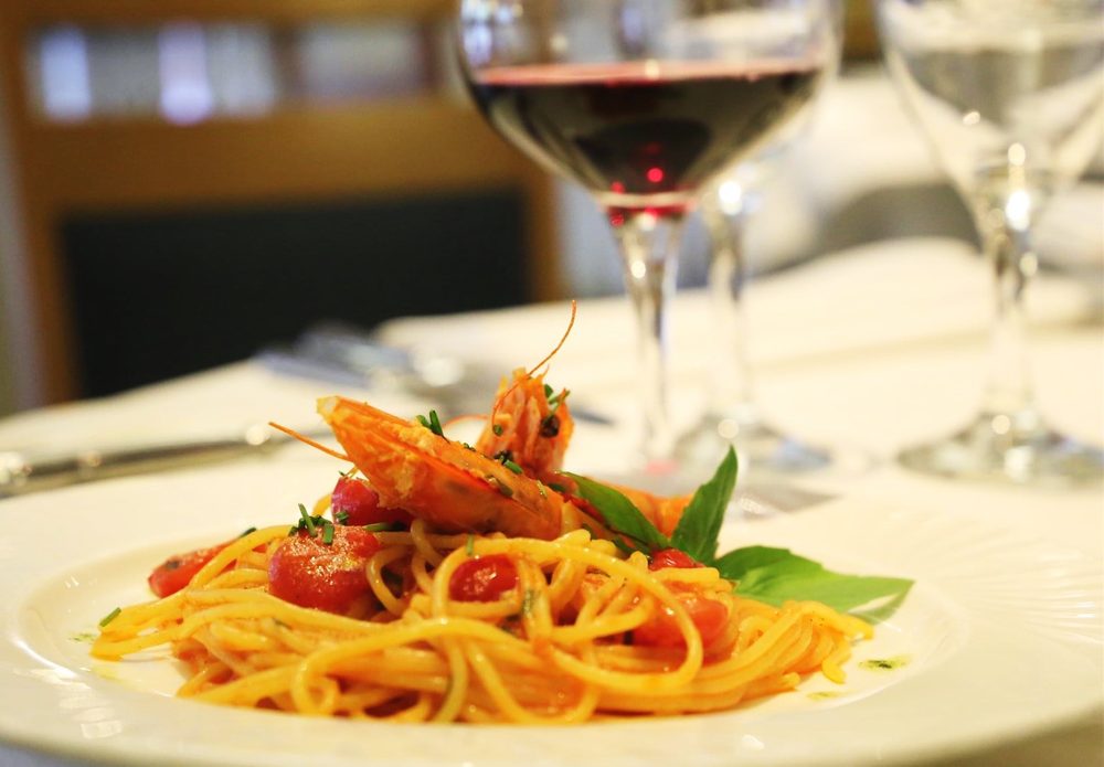 Spaghetti with king prawns and cherry tomatoes, served with a glass of red wine