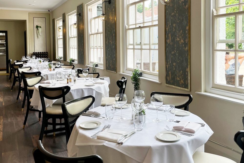 The bright, window-lit dining room at La Meridiana, laid for service